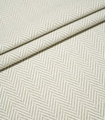 Layered folds of Bampton Argent herringbone fabric, highlighting the structured weave and repeating neutral grey-beige and off-white herringbone pattern.