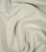Bampton Argent herringbone fabric loosely draped and gathered, demonstrating the fabric's natural movement, textured surface and neutral chevron design.