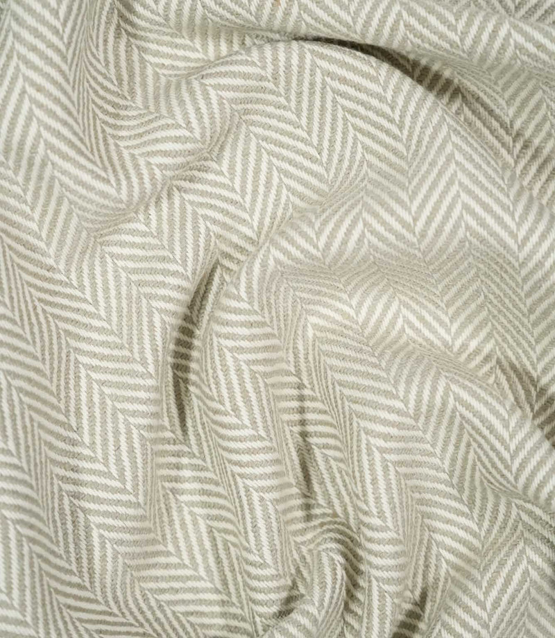 Bampton Argent herringbone fabric loosely draped and gathered, demonstrating the fabric's natural movement, textured surface and neutral chevron design.