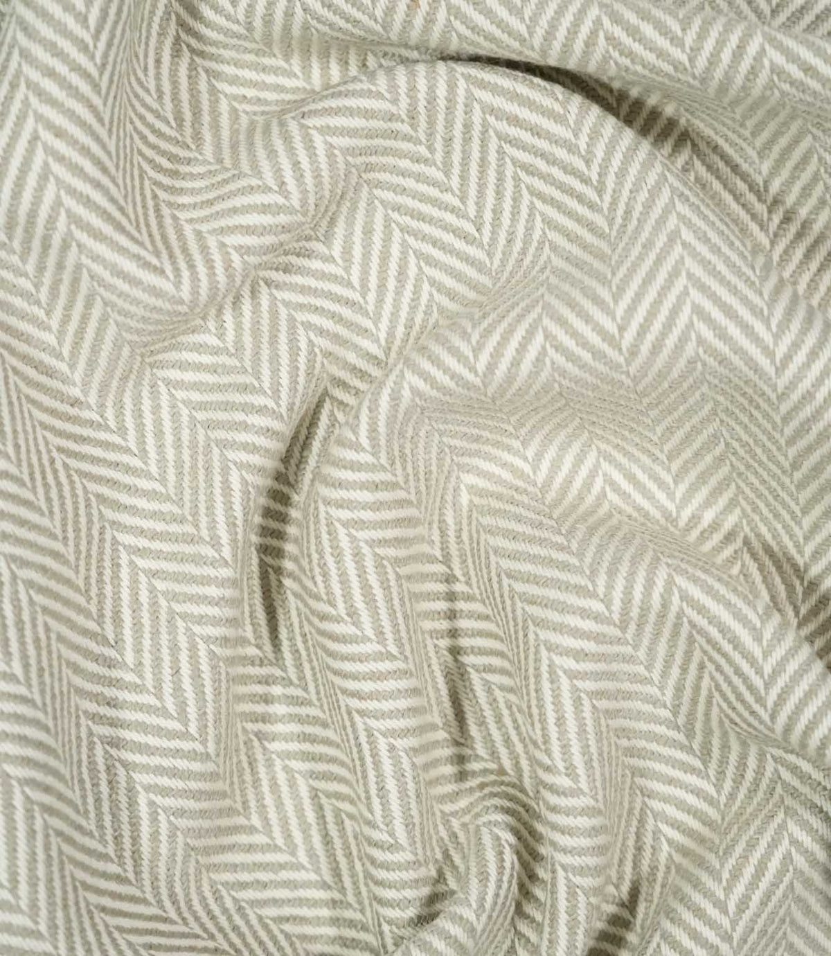 Bampton Argent herringbone fabric loosely draped and gathered, demonstrating the fabric's natural movement, textured surface and neutral chevron design.