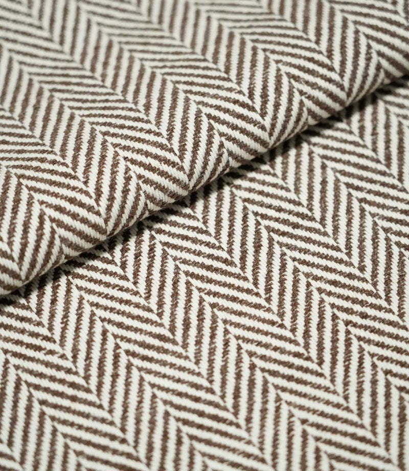 Close-up of folded Bampton Bison herringbone fabric, showing the substantial woven texture, fabric thickness and repeating brown and off-white chevron pattern.