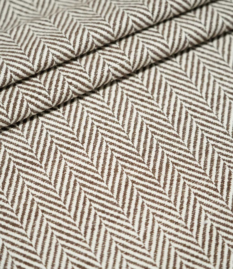Bampton Bison herringbone fabric arranged in layered folds, displaying the structured texture and repeating chocolate brown and off-white woven chevron design.
