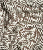 Bampton Bison herringbone fabric loosely draped and gathered, demonstrating the natural movement of the material and its distinctive brown and off-white herringbone pattern.