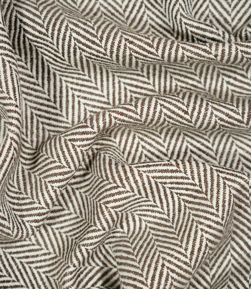 Bampton Bison herringbone fabric loosely draped and gathered, demonstrating the natural movement of the material and its distinctive brown and off-white herringbone pattern.