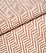Bampton Chestnut herringbone fabric arranged in a soft fold, highlighting the raised woven texture and contrasting chestnut orange and off-white herringbone design.