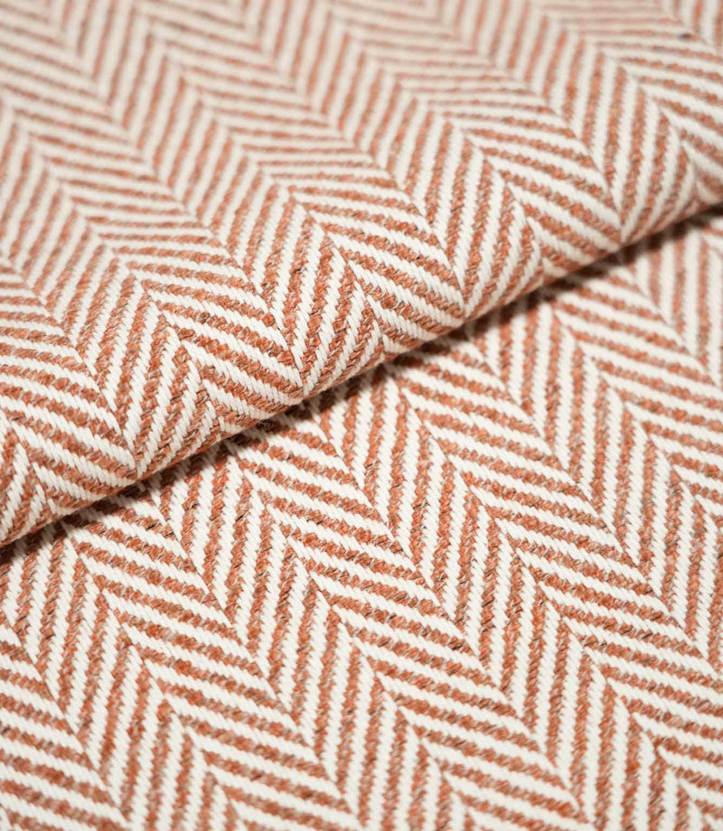 Bampton Chestnut herringbone fabric arranged in a soft fold, highlighting the raised woven texture and contrasting chestnut orange and off-white herringbone design.