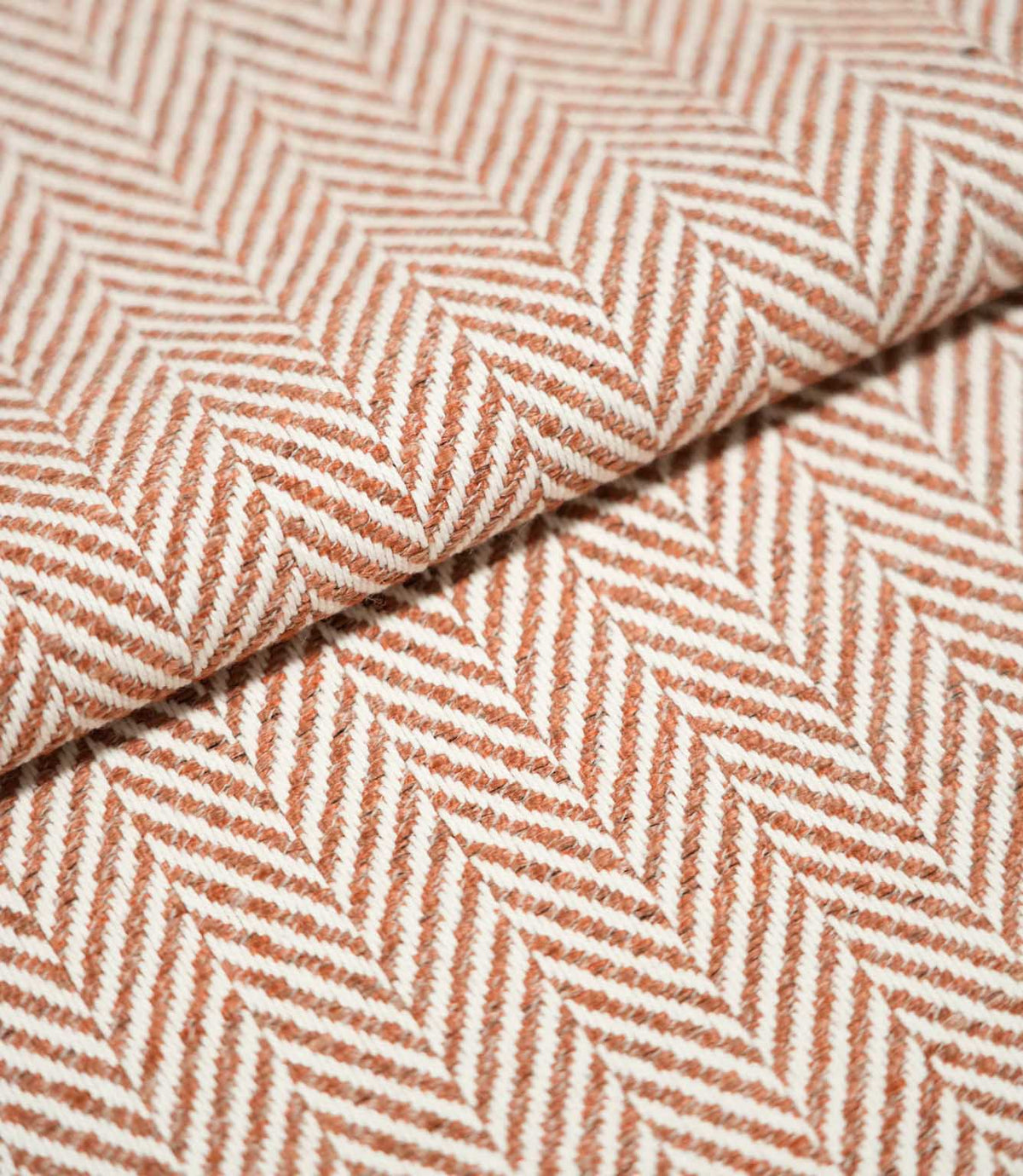 Bampton Chestnut herringbone fabric arranged in a soft fold, highlighting the raised woven texture and contrasting chestnut orange and off-white herringbone design.