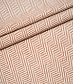 Layered folds of Bampton Chestnut herringbone fabric, showing the fabric's structure, thickness and repeating orange-brown and off-white chevron pattern.