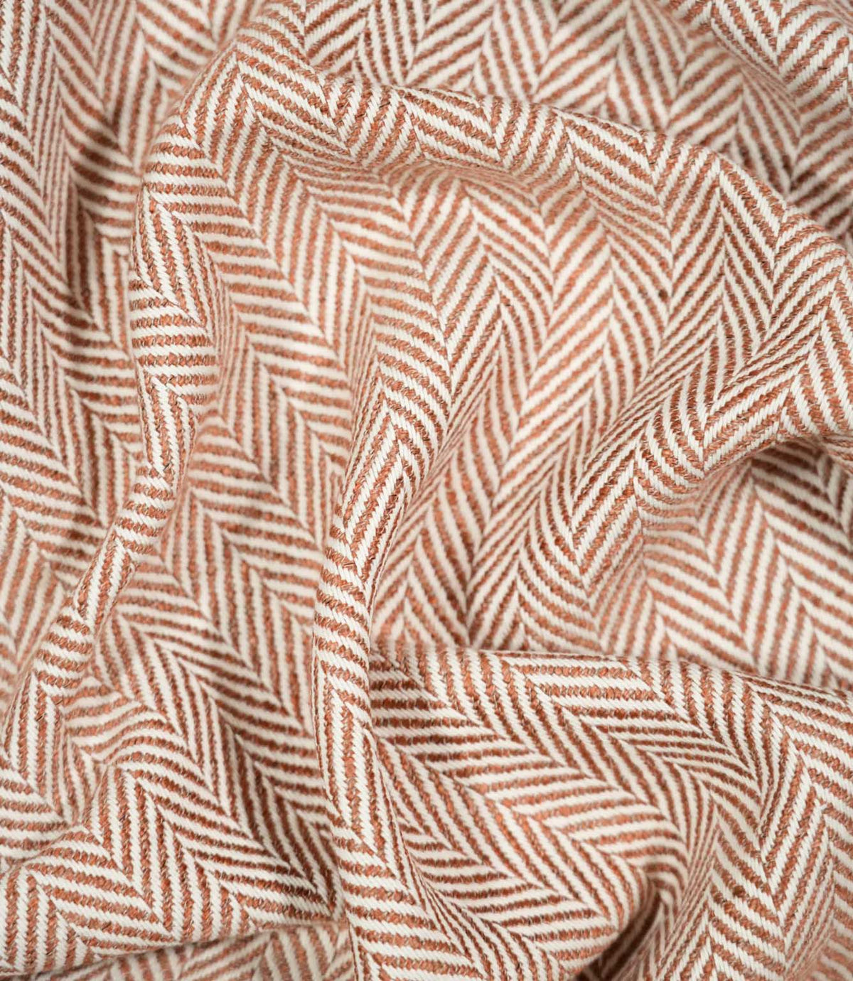 Bampton Chestnut herringbone fabric loosely draped and gathered, demonstrating its natural movement and distinctive chestnut orange and off-white woven pattern.