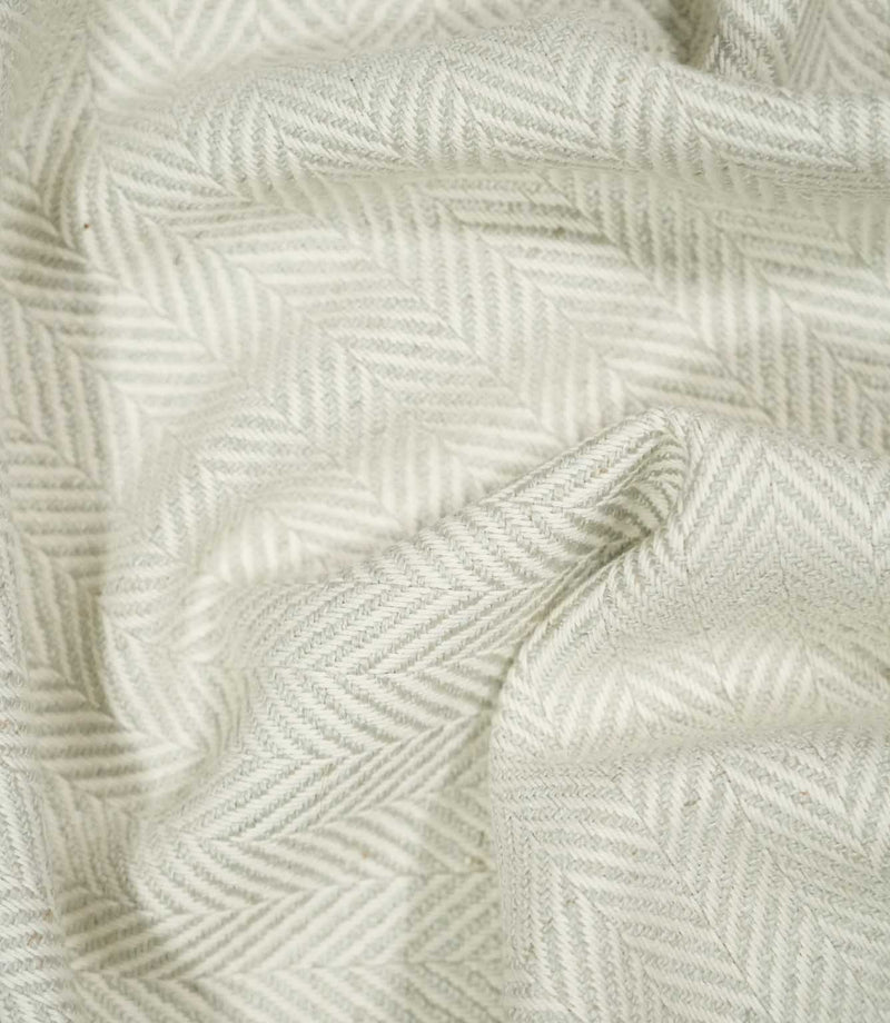 Bampton Elephant Grey herringbone fabric loosely draped and gathered, demonstrating its natural movement, soft neutral colouring and woven chevron design.