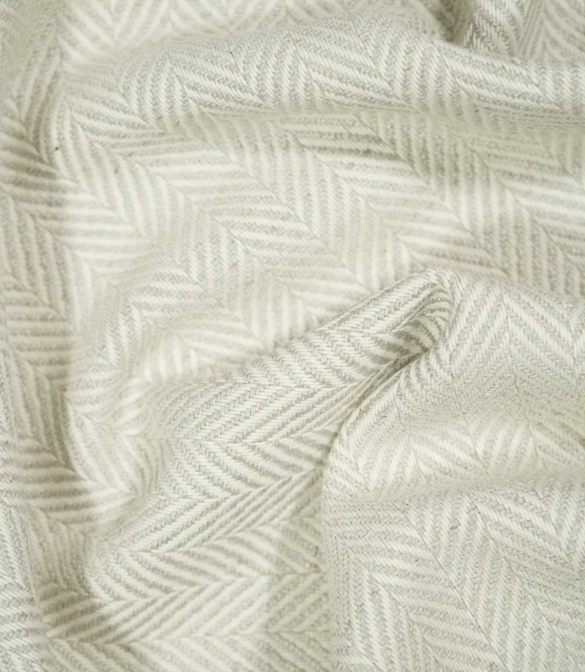 Bampton Elephant Grey herringbone fabric loosely draped and gathered, demonstrating its natural movement, soft neutral colouring and woven chevron design.