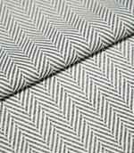 Close-up of folded Bampton Grey herringbone fabric, highlighting the structured woven texture, grey and off-white chevron pattern and fabric thickness.