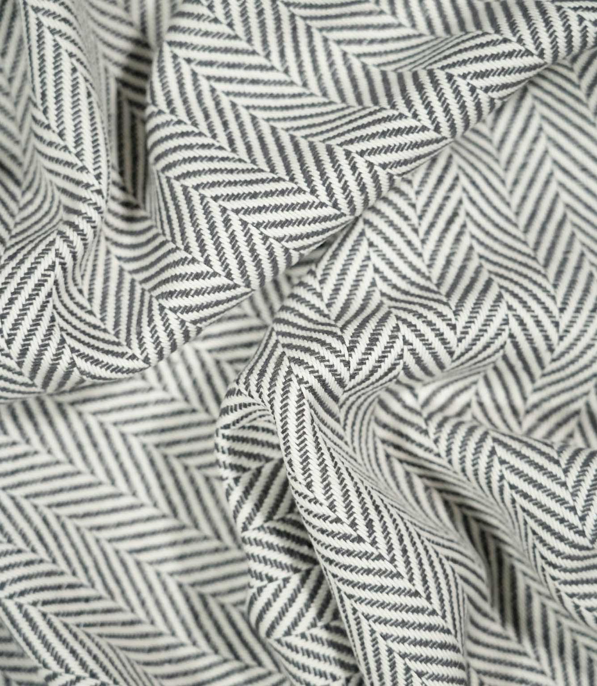 Bampton Grey herringbone fabric loosely draped and gathered, demonstrating how the textured woven material falls naturally while retaining its distinctive chevron pattern.