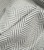 Macro close-up of draped Bampton Grey herringbone fabric, highlighting the raised woven texture, individual threads and crisp grey and off-white chevron design.