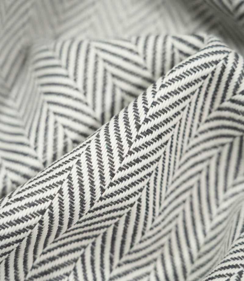 Macro close-up of draped Bampton Grey herringbone fabric, highlighting the raised woven texture, individual threads and crisp grey and off-white chevron design.