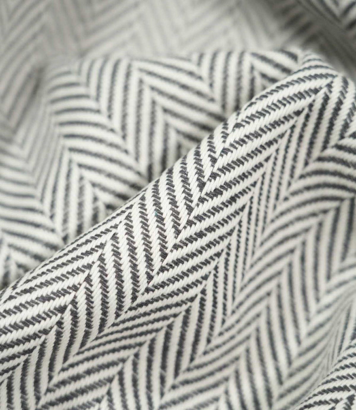Macro close-up of draped Bampton Grey herringbone fabric, highlighting the raised woven texture, individual threads and crisp grey and off-white chevron design.