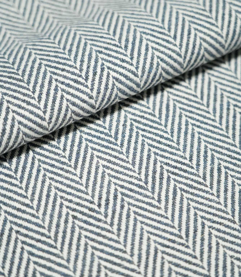 Close-up of folded Bampton Ink herringbone fabric, showing its substantial woven texture and repeating navy blue and off-white chevron design.