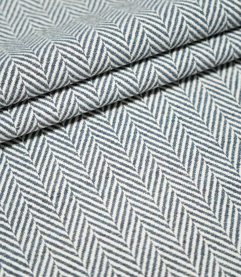 Layered folds of Bampton Ink herringbone fabric, highlighting the structured weave, thickness and contrasting navy blue and off-white herringbone pattern.