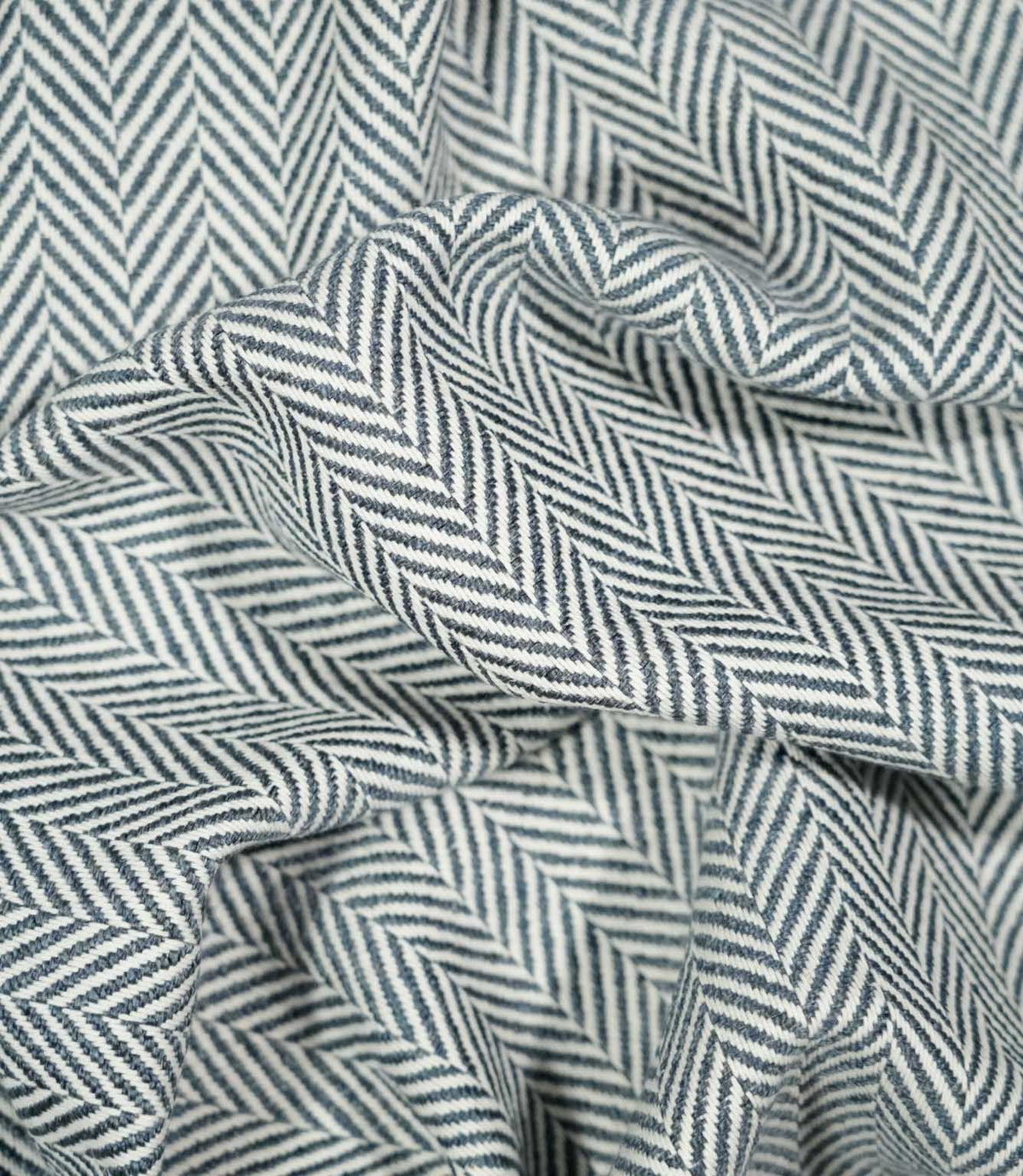 Bampton Ink herringbone fabric loosely draped and gathered, demonstrating its natural movement and bold repeating navy blue and off-white chevron design.