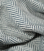 Macro close-up of draped Bampton Ink herringbone fabric, highlighting the individual woven fibres, fabric thickness and detailed navy blue and off-white herringbone pattern.