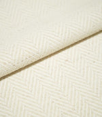 Close-up of folded Bampton Jasmine herringbone fabric, showing the thickness of the material and its subtle cream chevron weave with natural flecked detail.