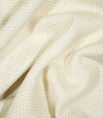 Bampton Jasmine herringbone fabric loosely draped and gathered, demonstrating the natural movement of the material and its subtle cream woven chevron pattern.