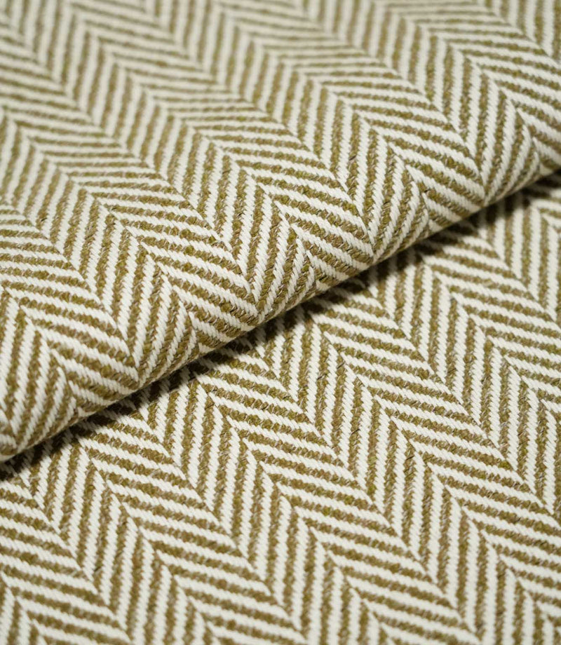 Close-up of folded Bampton Matcha herringbone fabric, showing the substantial woven texture, fabric thickness and repeating olive green and off-white chevron pattern.