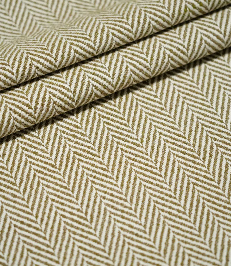 Bampton Matcha herringbone fabric arranged in layered folds, displaying the structured texture and repeating olive green and off-white woven chevron design.
