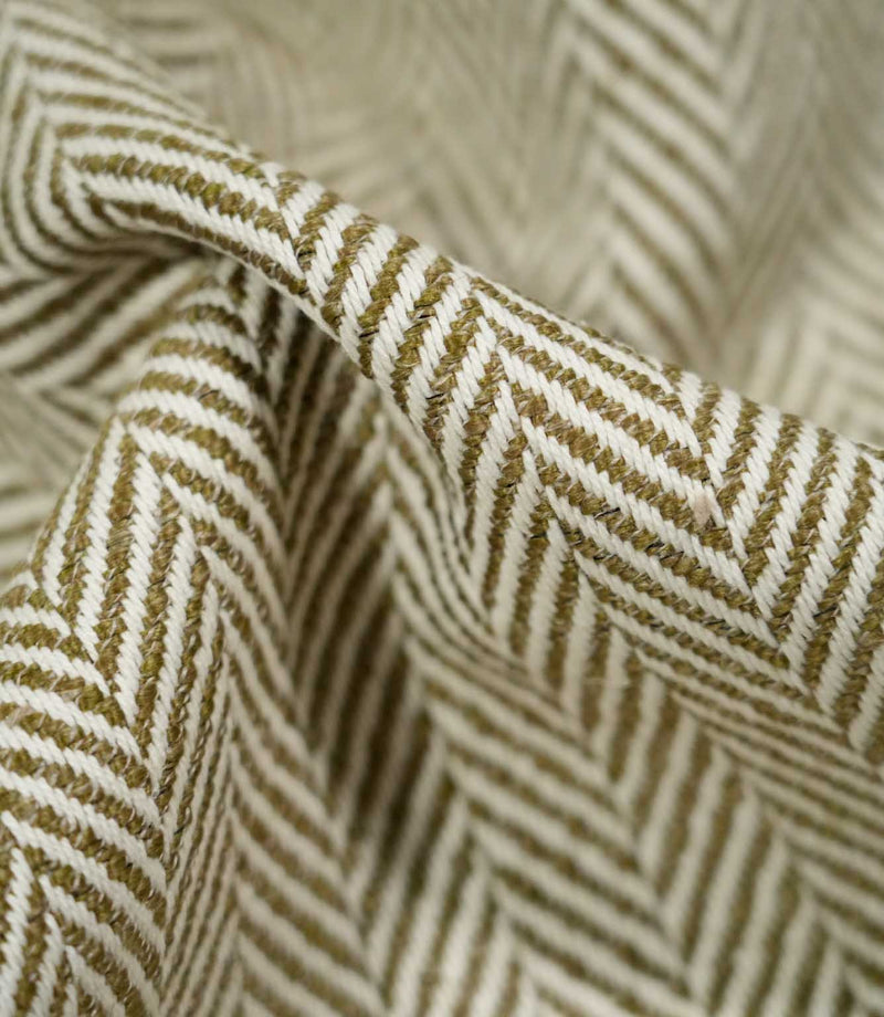 Macro close-up of draped Bampton Matcha herringbone fabric, highlighting the individual woven fibres, raised texture and detailed olive green and off-white chevron design.