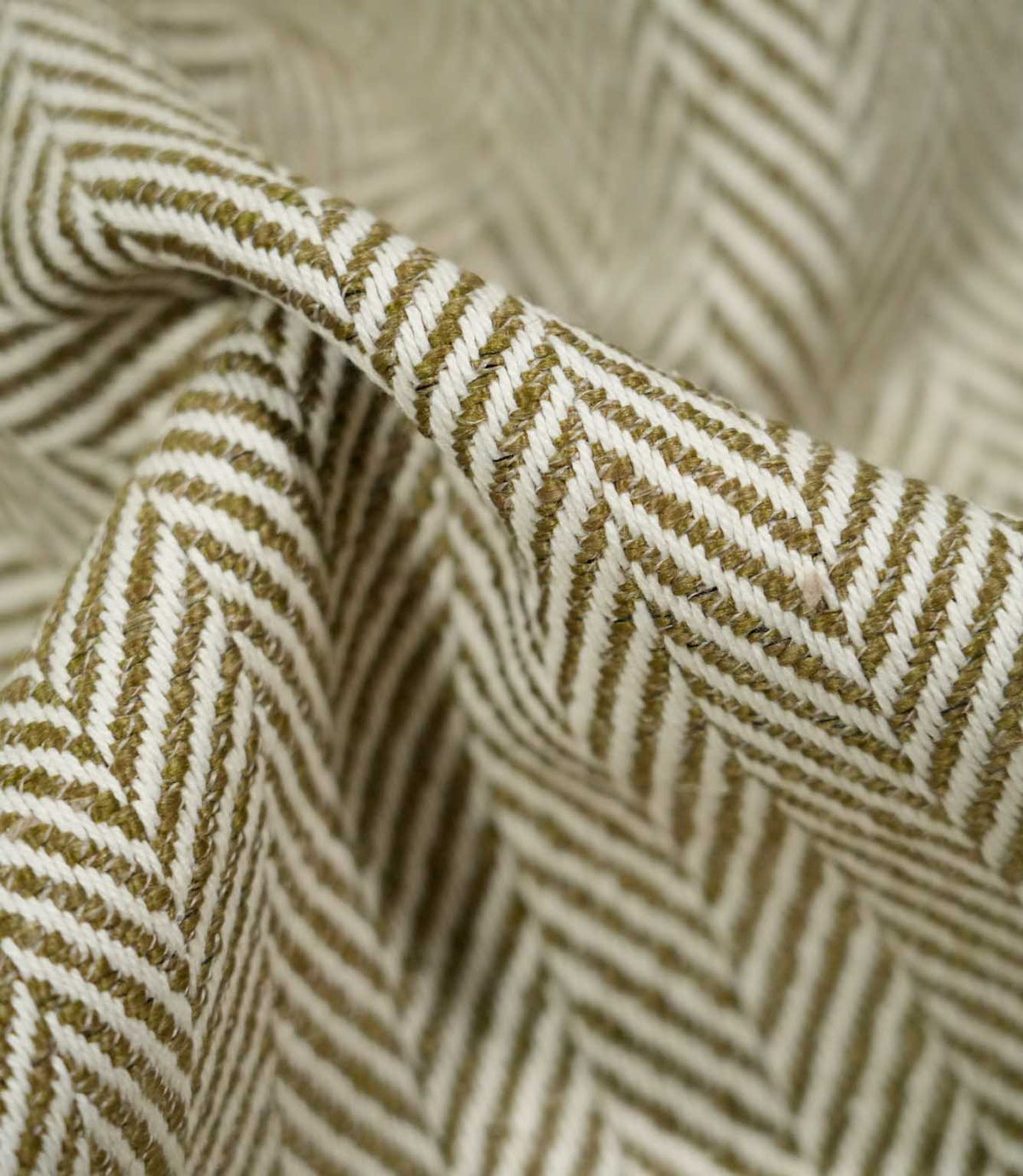 Macro close-up of draped Bampton Matcha herringbone fabric, highlighting the individual woven fibres, raised texture and detailed olive green and off-white chevron design.