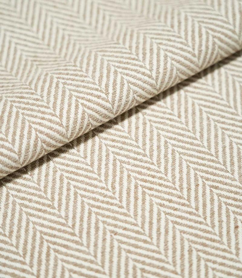 Close-up of folded Bampton Taupe herringbone fabric, showing the warm taupe and off-white chevron pattern, raised woven texture and substantial finish.