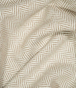 Bampton Taupe herringbone fabric loosely draped into soft folds, demonstrating its natural movement, warm neutral tones and defined woven pattern.