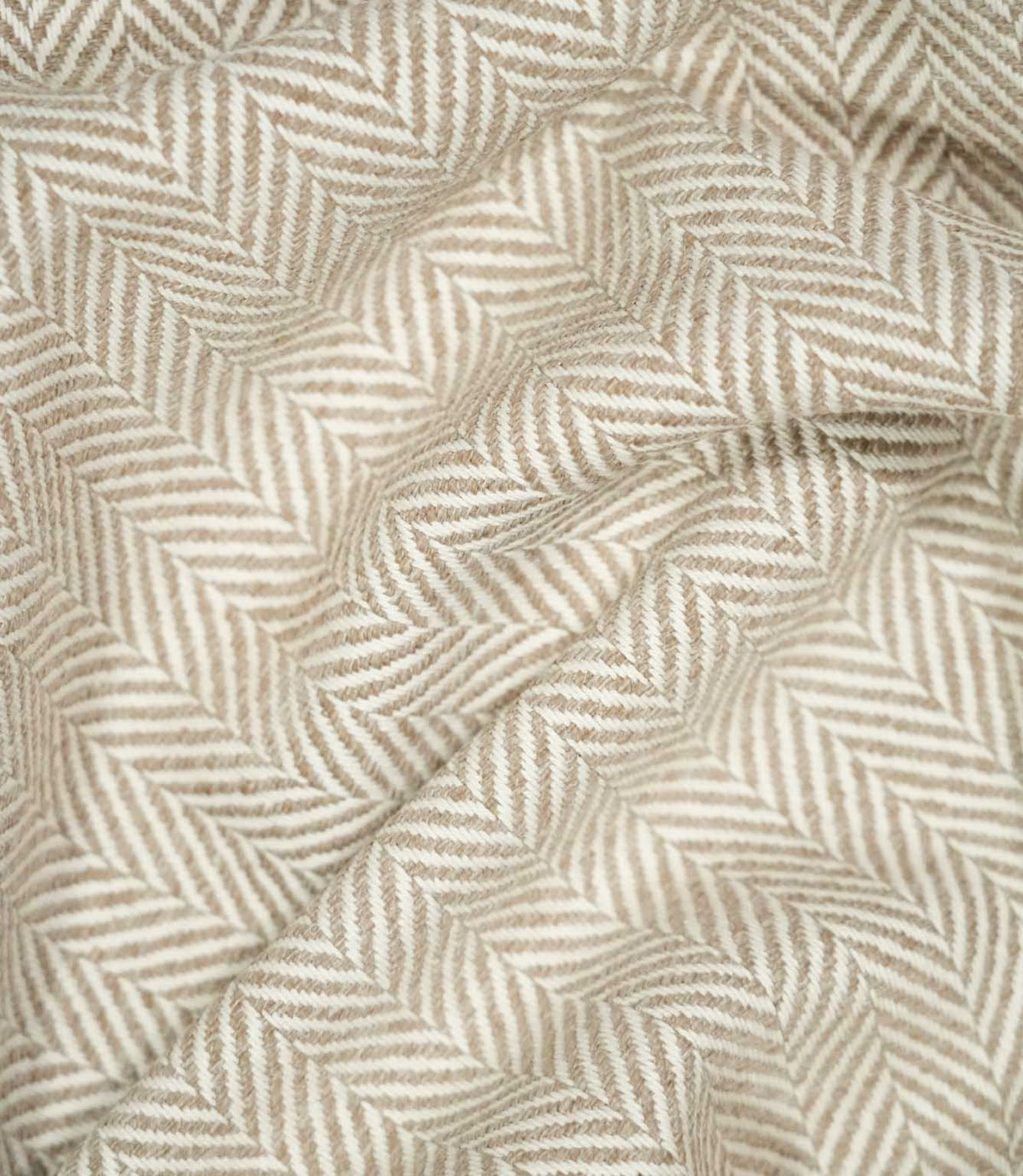 Bampton Taupe herringbone fabric loosely draped into soft folds, demonstrating its natural movement, warm neutral tones and defined woven pattern.