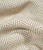 Macro close-up of draped Bampton Taupe herringbone fabric, revealing the detailed taupe and off-white weave, tactile texture and definition of the chevron pattern.