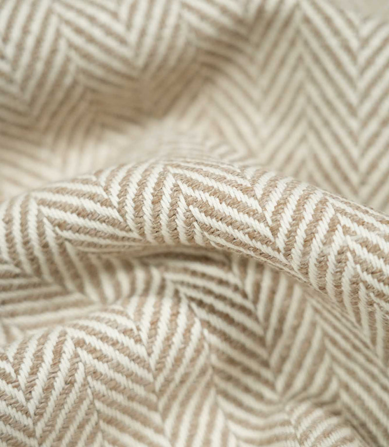 Macro close-up of draped Bampton Taupe herringbone fabric, revealing the detailed taupe and off-white weave, tactile texture and definition of the chevron pattern.