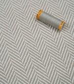 Bampton Argent woven herringbone upholstery fabric with matching grey sewing thread, highlighting the elegant chevron weave for upholstery and soft furnishing projects.
