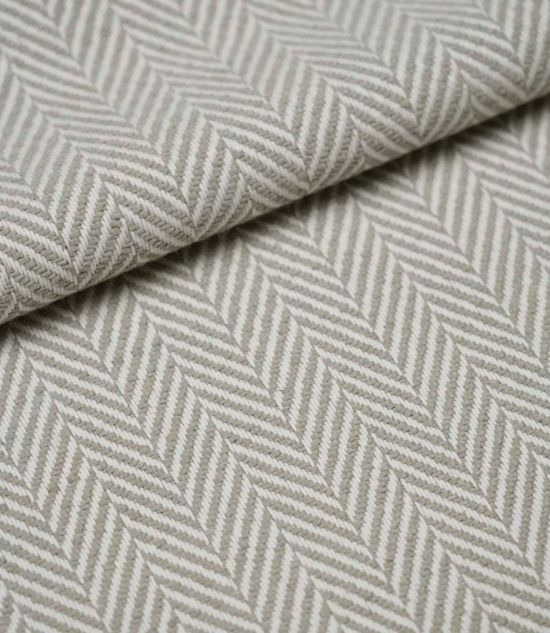 Folded Bampton Argent upholstery fabric displaying the textured woven herringbone pattern and soft drape, ideal for curtains, cushions and upholstery.