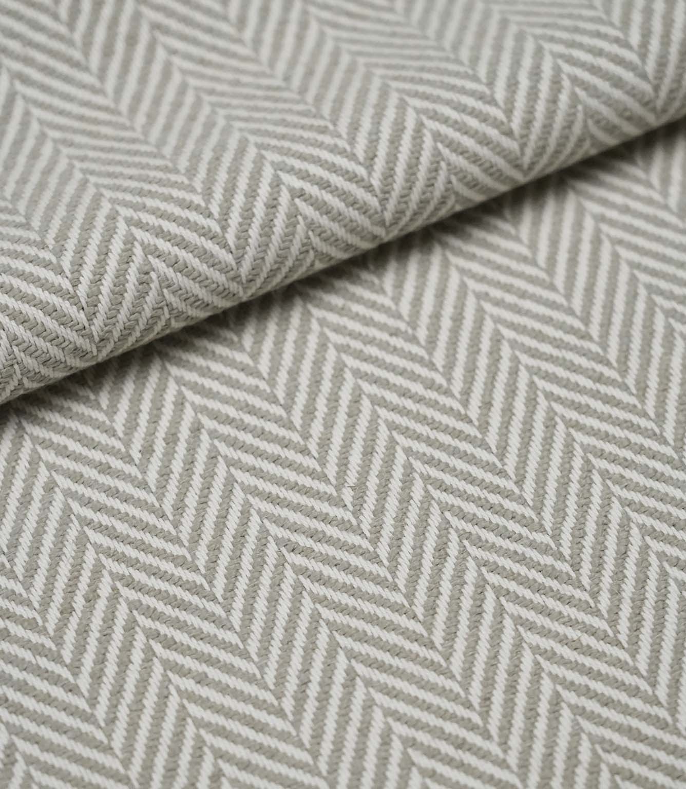 Folded Bampton Argent upholstery fabric displaying the textured woven herringbone pattern and soft drape, ideal for curtains, cushions and upholstery.