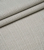 Layered Bampton Argent woven fabric featuring a timeless chevron herringbone design with a textured finish, suitable for premium upholstery and interior projects.