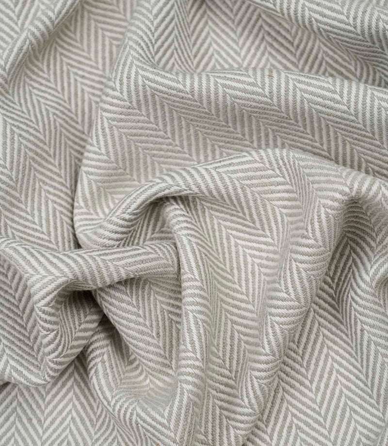 Draped Bampton Argent woven upholstery fabric showing its elegant natural drape, textured herringbone weave and sophisticated grey and ivory chevron design.