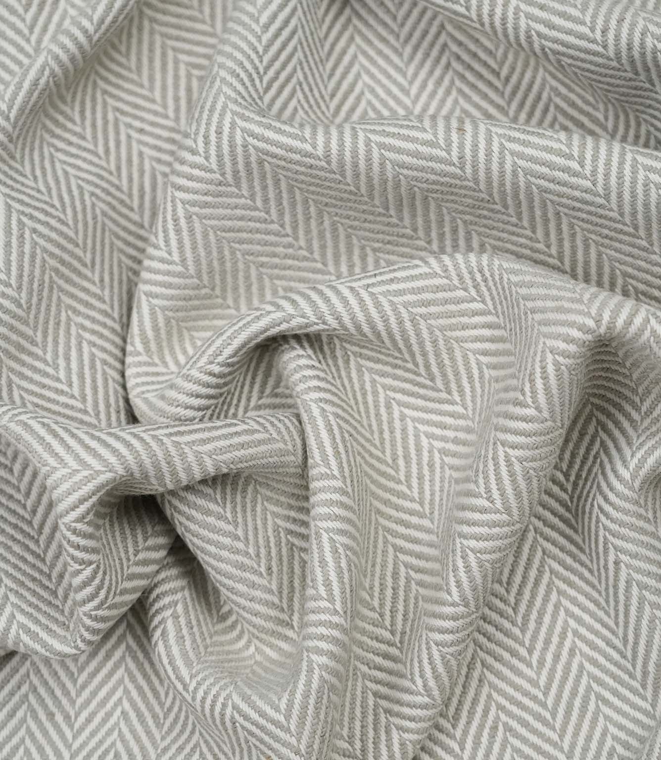 Draped Bampton Argent woven upholstery fabric showing its elegant natural drape, textured herringbone weave and sophisticated grey and ivory chevron design.