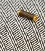 Bampton Bison herringbone fabric with a matching brown thread spool, showcasing the woven texture and coordinated colour.
