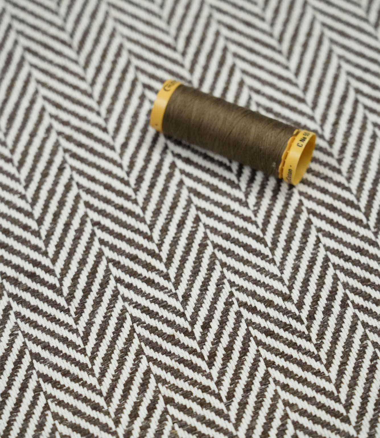 Bampton Bison herringbone fabric with a matching brown thread spool, showcasing the woven texture and coordinated colour.