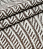 Layered folds of Bampton Bison upholstery fabric showing the depth, texture and repeating woven herringbone design.