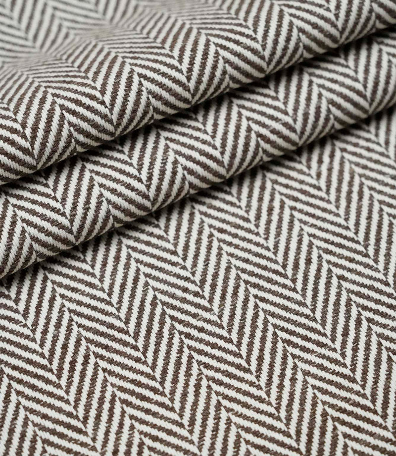 Layered folds of Bampton Bison upholstery fabric showing the depth, texture and repeating woven herringbone design.