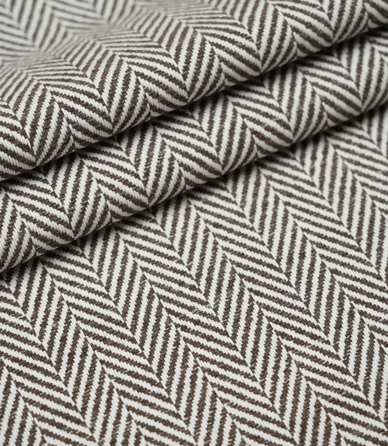 Layered folds of Bampton Bison upholstery fabric showing the depth, texture and repeating woven herringbone design.