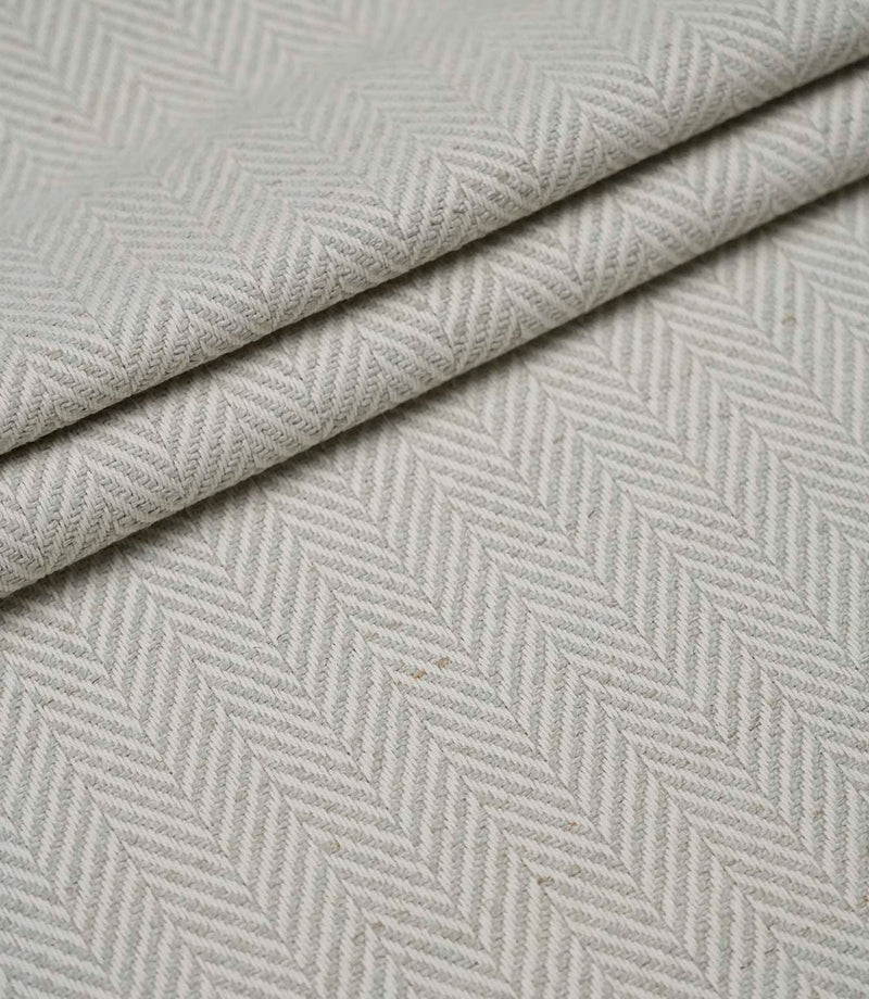 Layered Bampton Elephant Grey woven fabric featuring a subtle chevron herringbone design in elephant grey and ivory, perfect for upholstery and home décor projects.