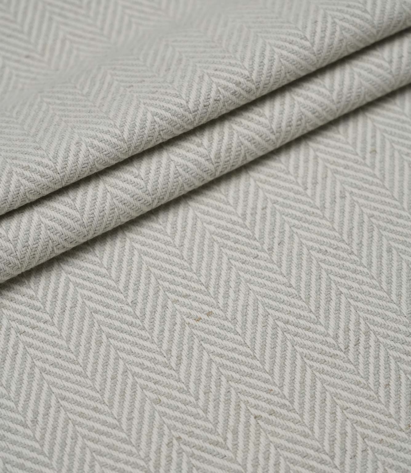 Layered Bampton Elephant Grey woven fabric featuring a subtle chevron herringbone design in elephant grey and ivory, perfect for upholstery and home décor projects.