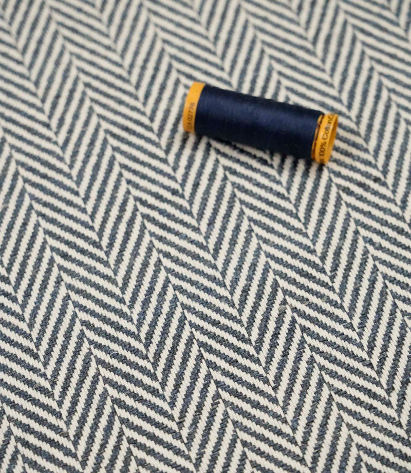 Bampton Ink woven herringbone upholstery fabric with matching navy sewing thread, highlighting the textured chevron weave for upholstery and soft furnishing projects.
