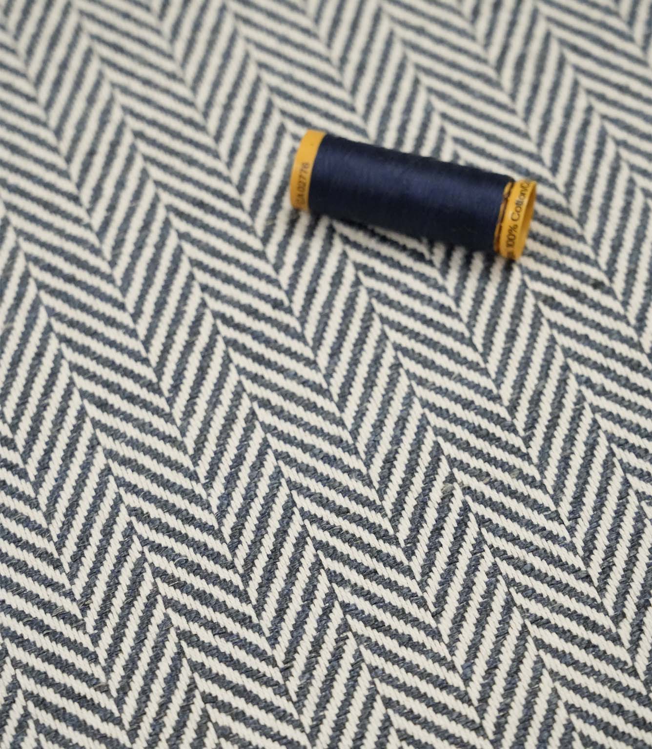 Bampton Ink woven herringbone upholstery fabric with matching navy sewing thread, highlighting the textured chevron weave for upholstery and soft furnishing projects.